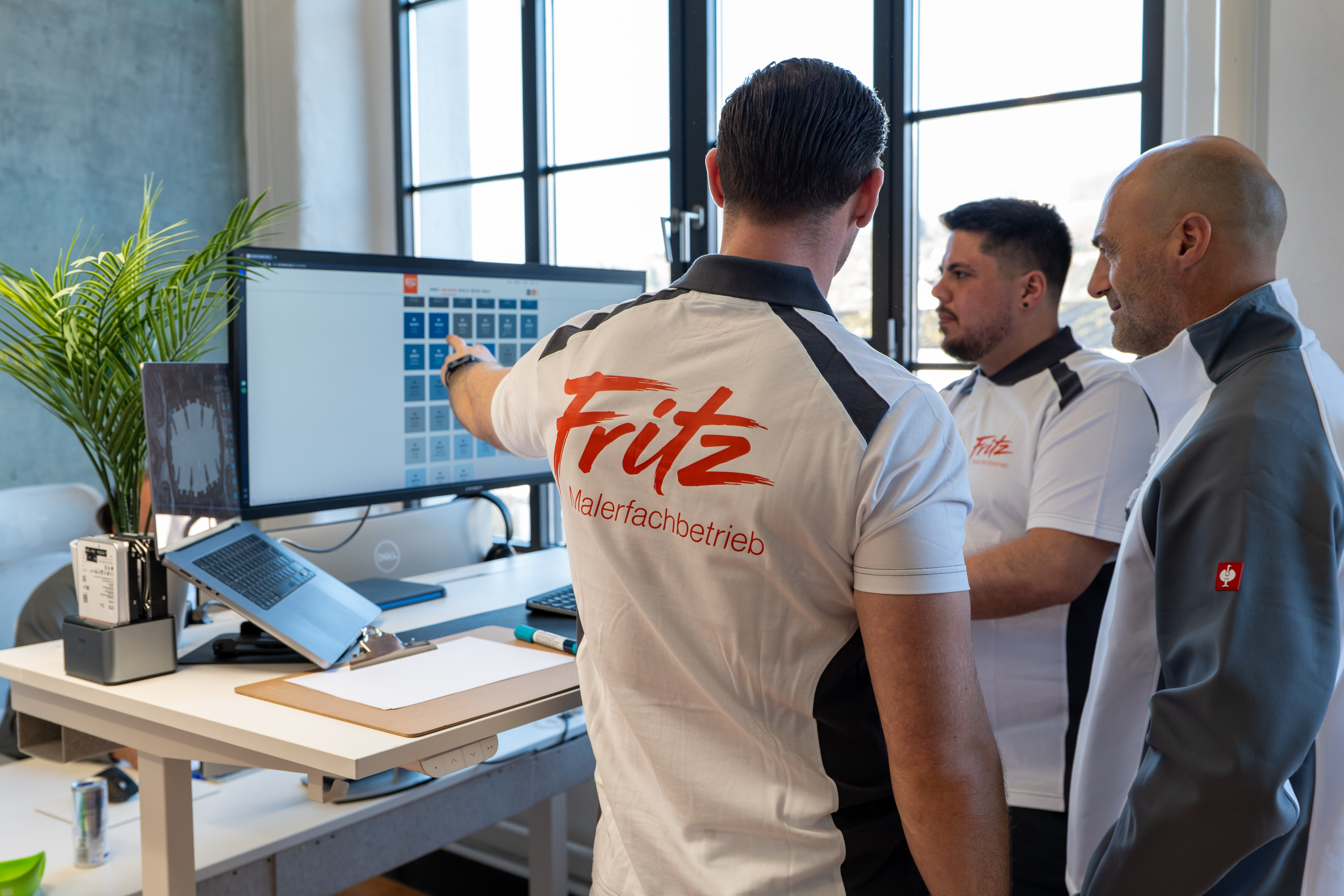 Das Team von Fritz Malerfachbetrieb plant am Monitor digitale Projekte und bespricht wichtige Details