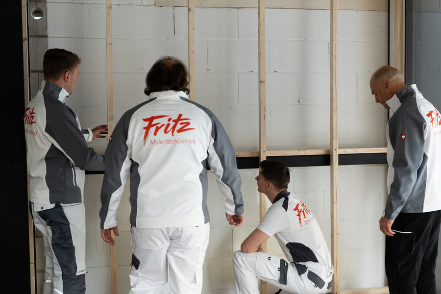Team von Fritz Malerfachbetrieb überprüft eine Wandkonstruktion aus Holz und Blocksteinen im Rohbau
